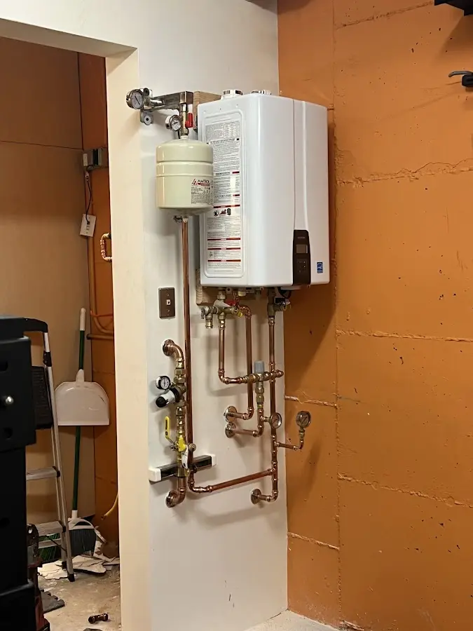 Plumbing technician inspecting water heater connections in Hoosick
